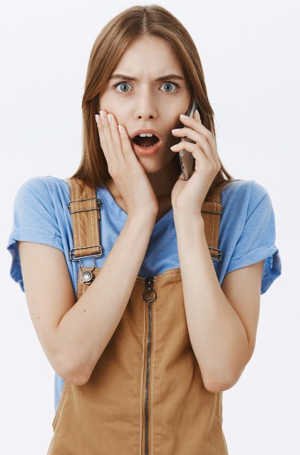 Woman looking surprised while talking on the phone